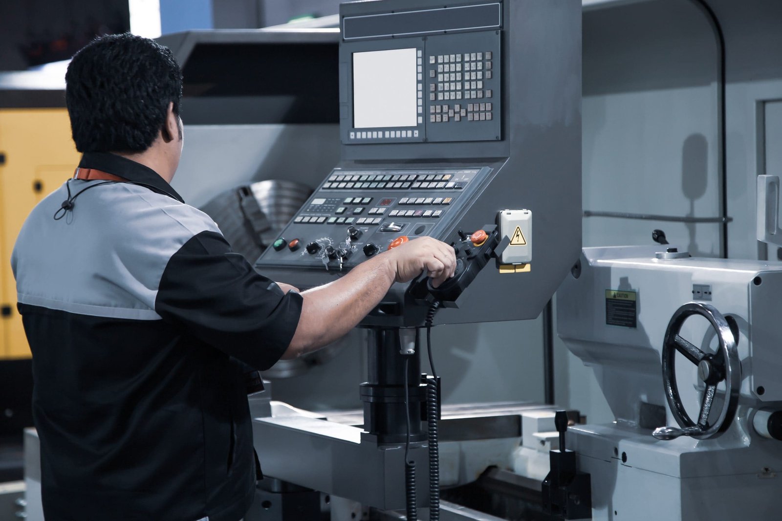 Industrial technician operating CNC lathing machine
